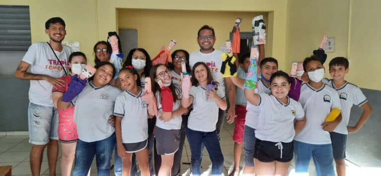 Grupo de crianças posando com bonecos feitos por eles.