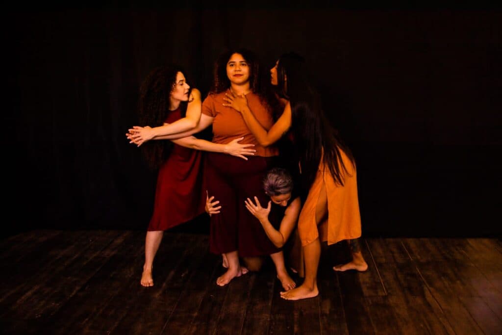 Grupo de quatro bailarinas em cena, com poses expressivas.