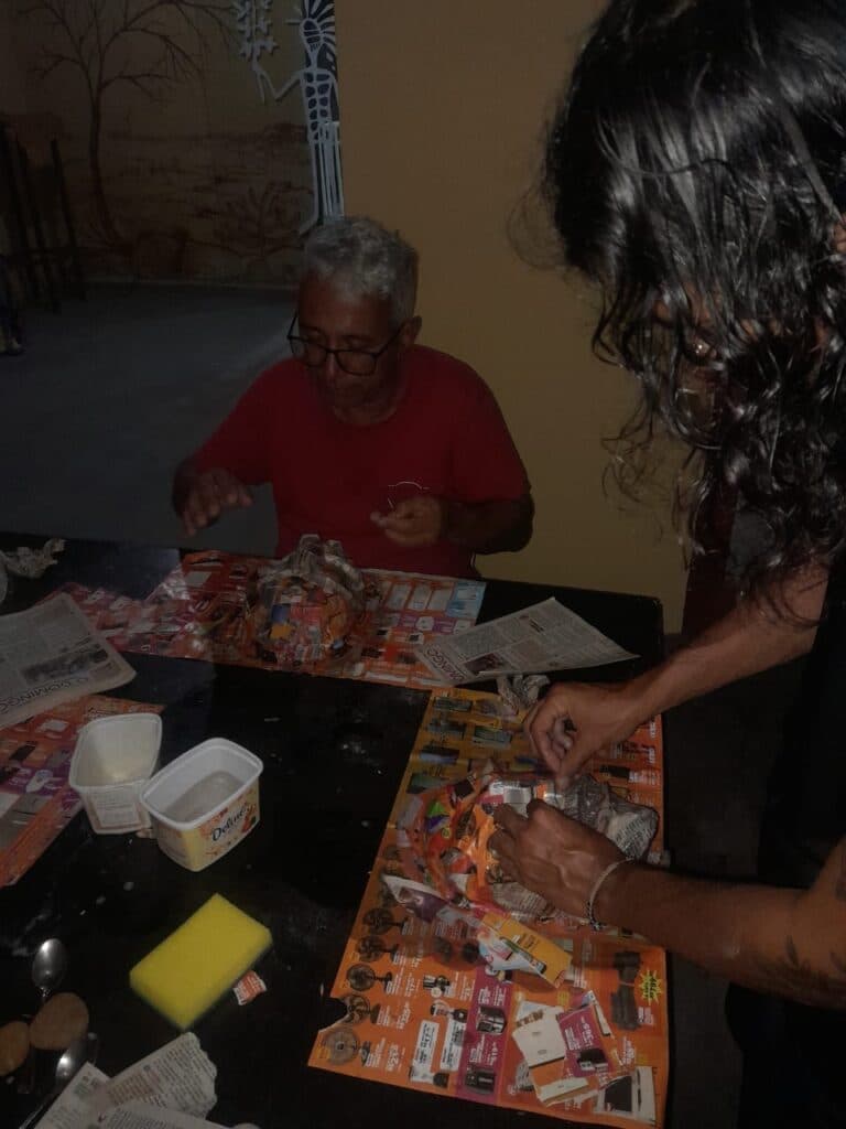 Participantes da Oficina de Artesanato em Papel para Adultos e Idosos juntos em uma mesa fazendo arte em papel.