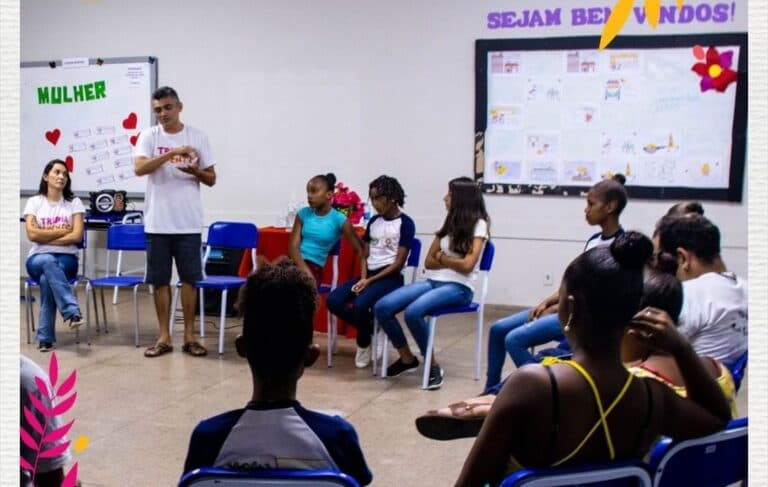 Professor falando para grupo de crianças em sala de aula.
